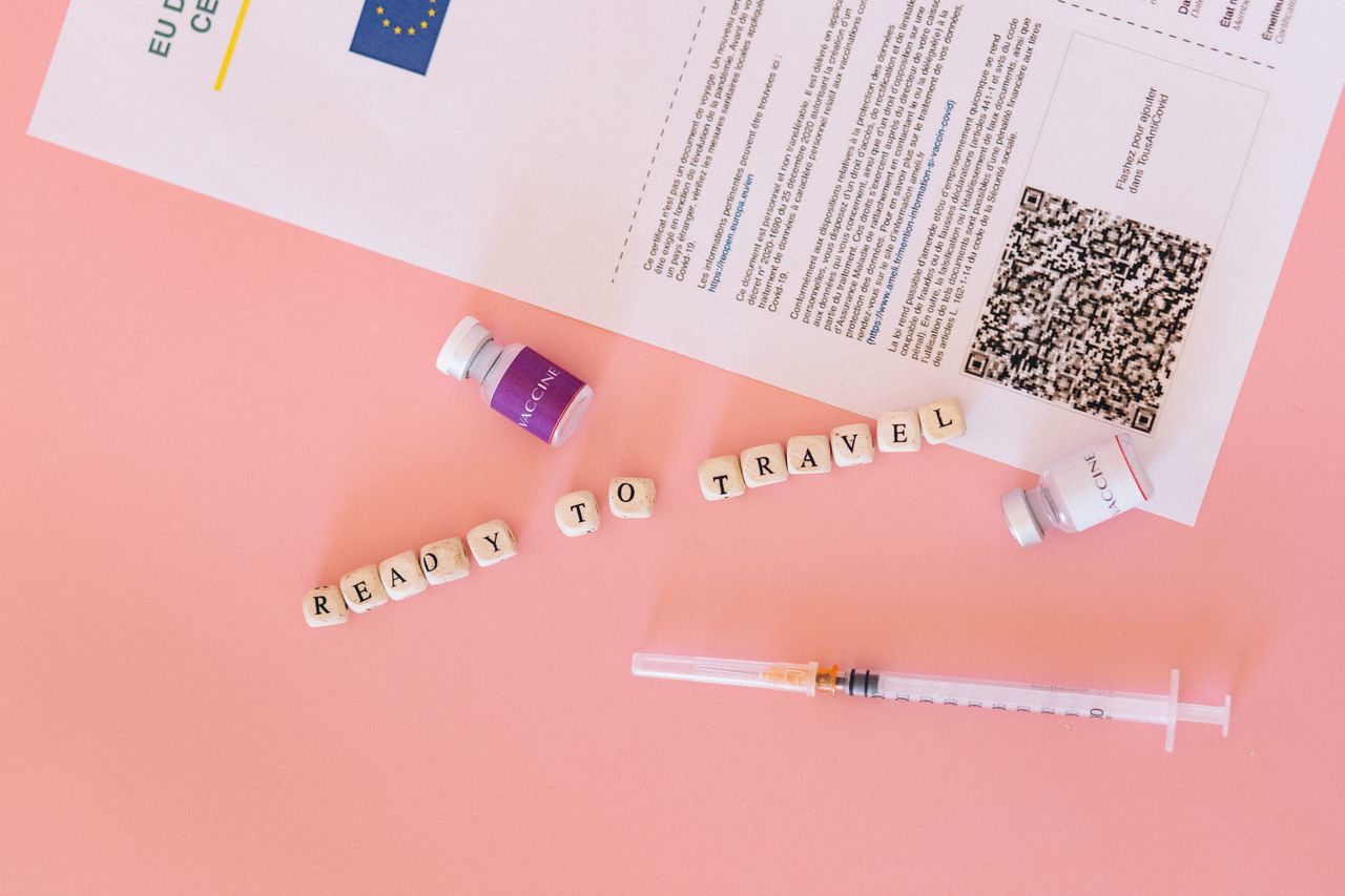 Hand ticking off items on a volunteer travel admin checklist with passport and visa nearby