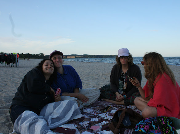 Four volunteers smiling for a photo beside the water at sunset