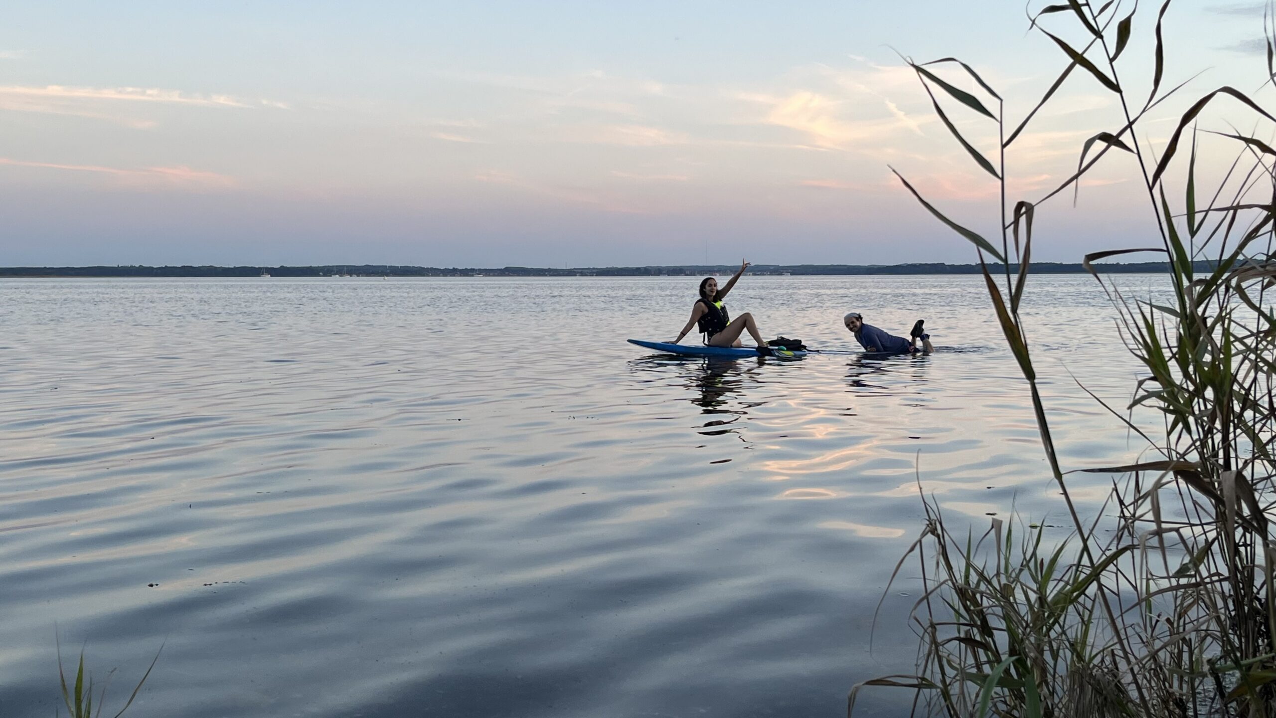 Two volunteers sitting together on a dock at sunset